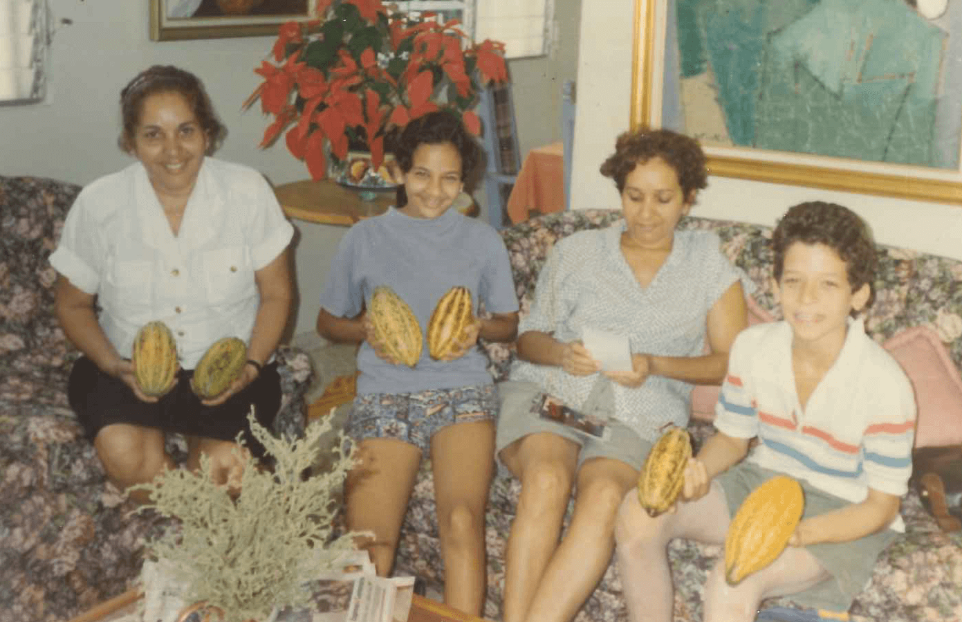 the Camilo family posing with cacao pods while sitting on a couch.